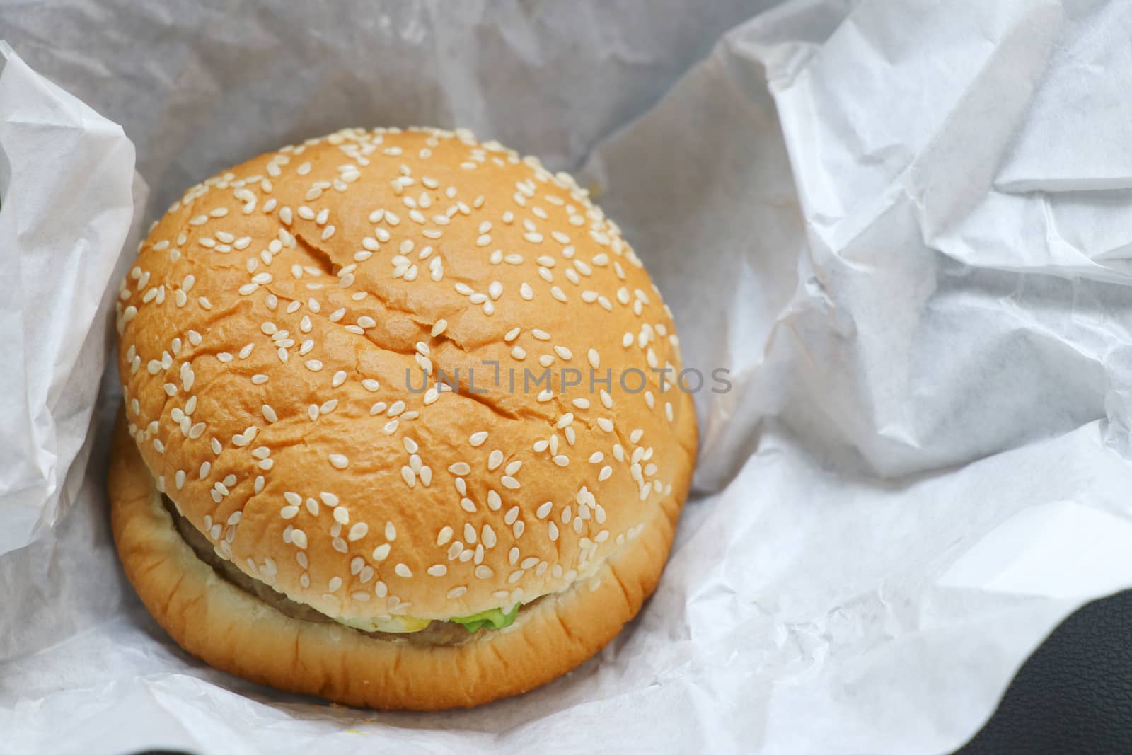 The hamburger is placed on white paper. Hamburger with white sesame sprinkled on top.