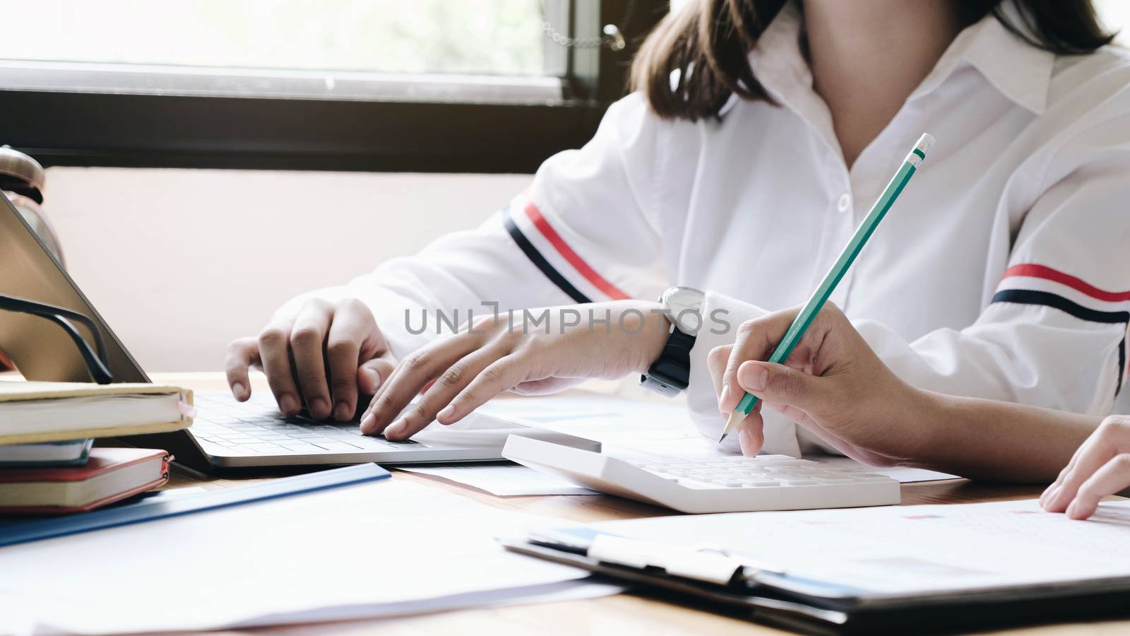 Business woman analysis on data paper with business man using calculator at the office, Business finance concept
