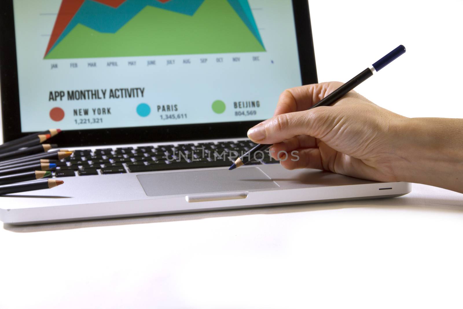 Digital or traditional graphic arts? A woman's hand seems to draw on the touch pad of a laptop computer with lots of colored pencils resting on the side