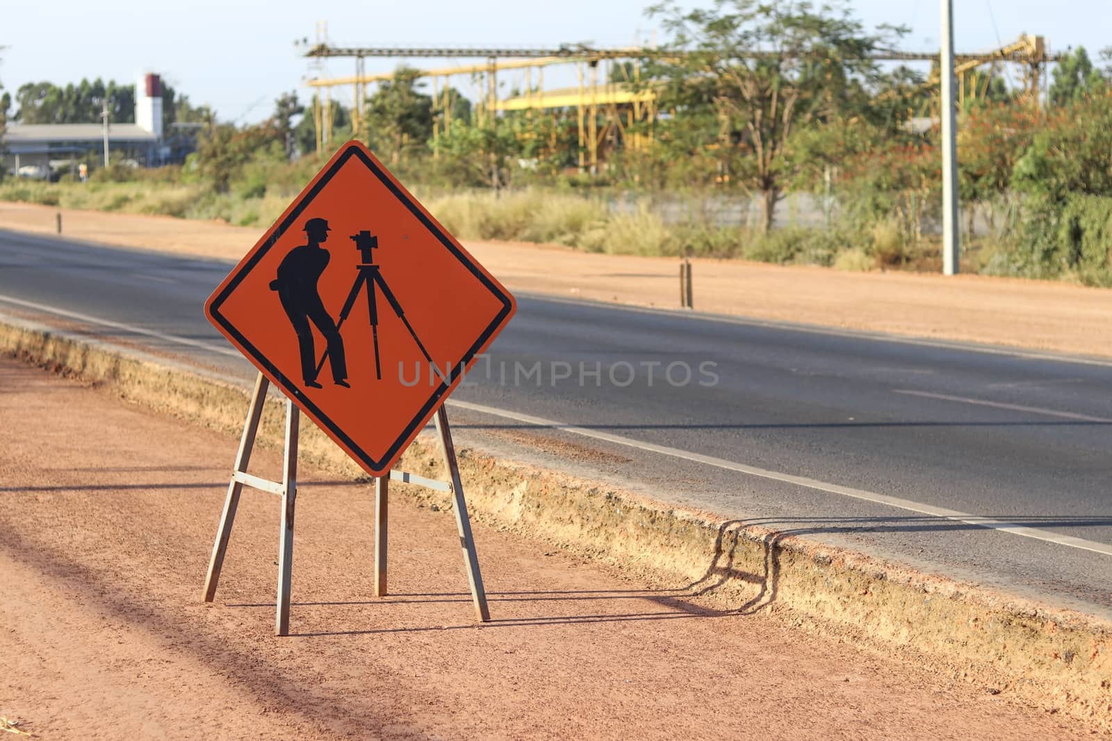 Orange label with pictograms survey engineering inside placed along the road under construction. by Eungsuwat