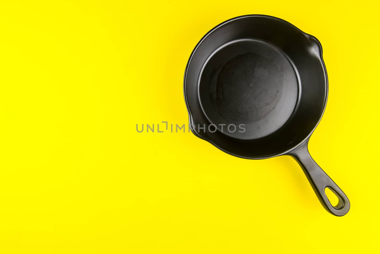 Black small pan on yellow background with copy space by Bubbers