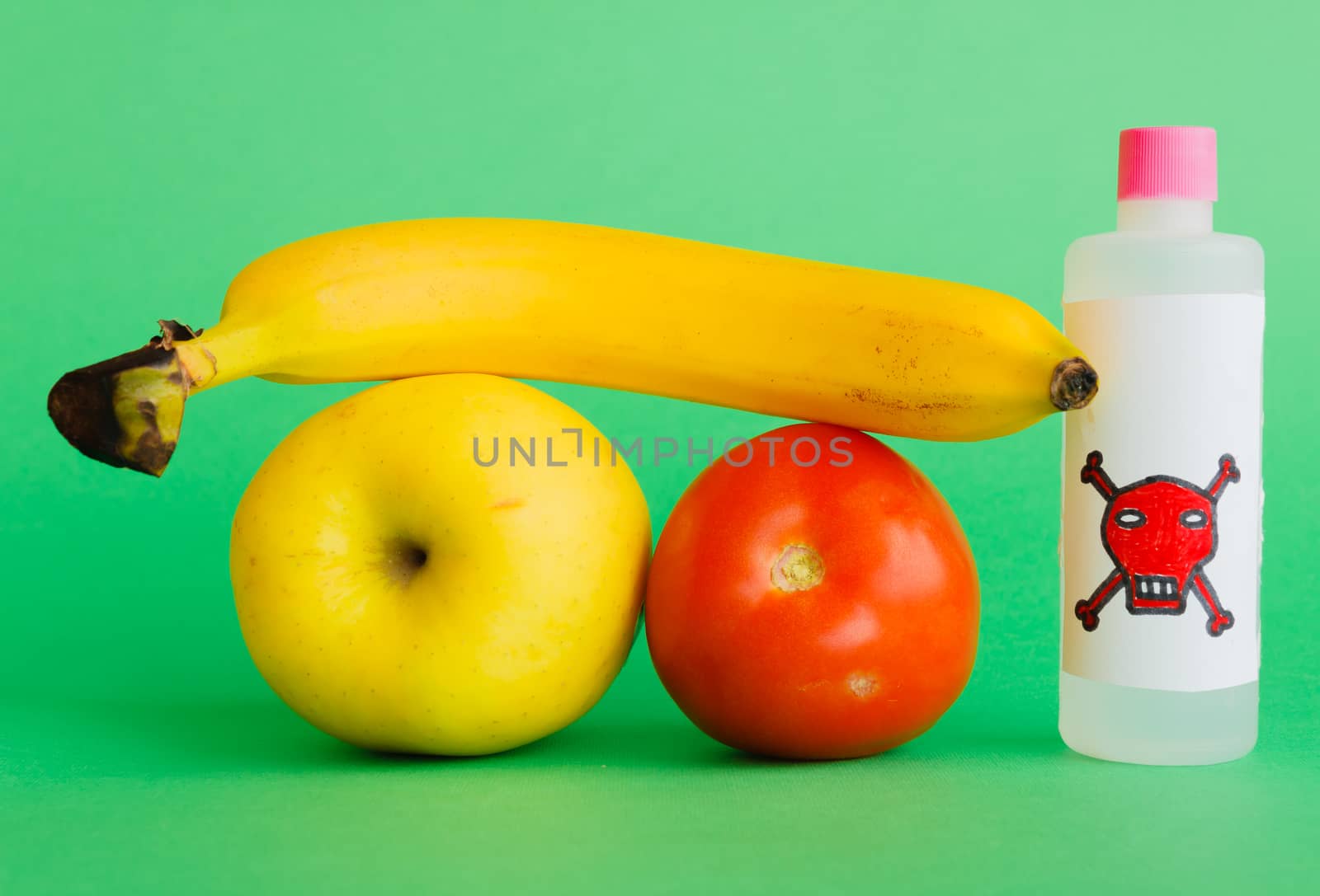 an apple, a banana and a tomato with a bottle that contains pesticides with the symbol of death