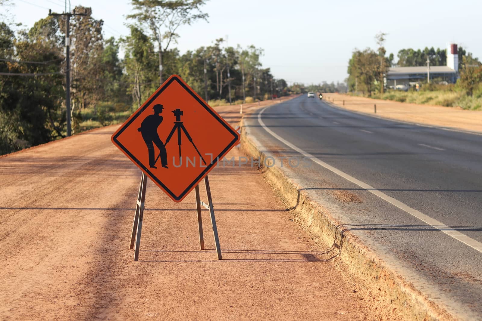 Orange label with pictograms survey engineering inside placed along the road under construction. by Eungsuwat