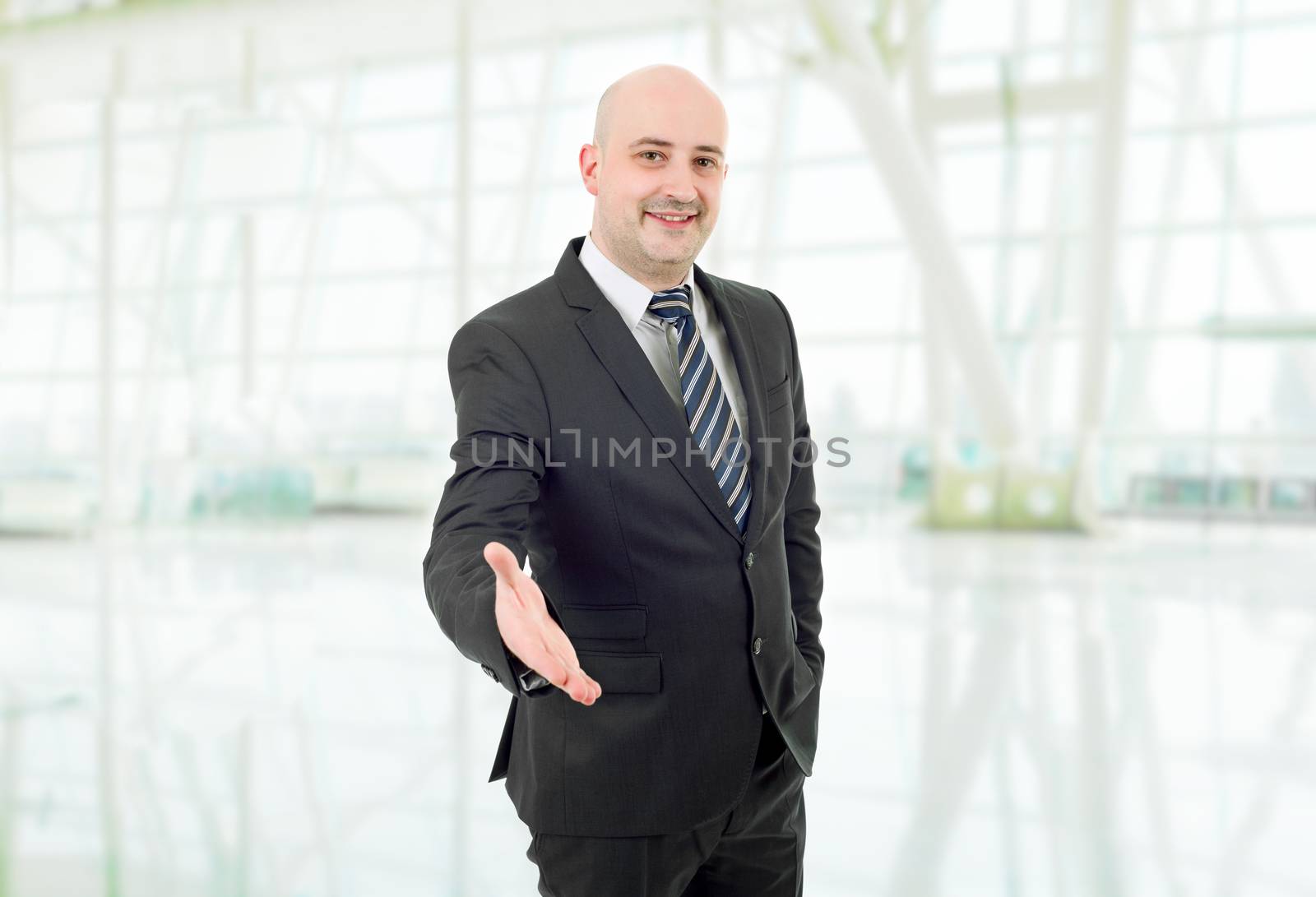 businessman in suit offering to shake the hand, at the office