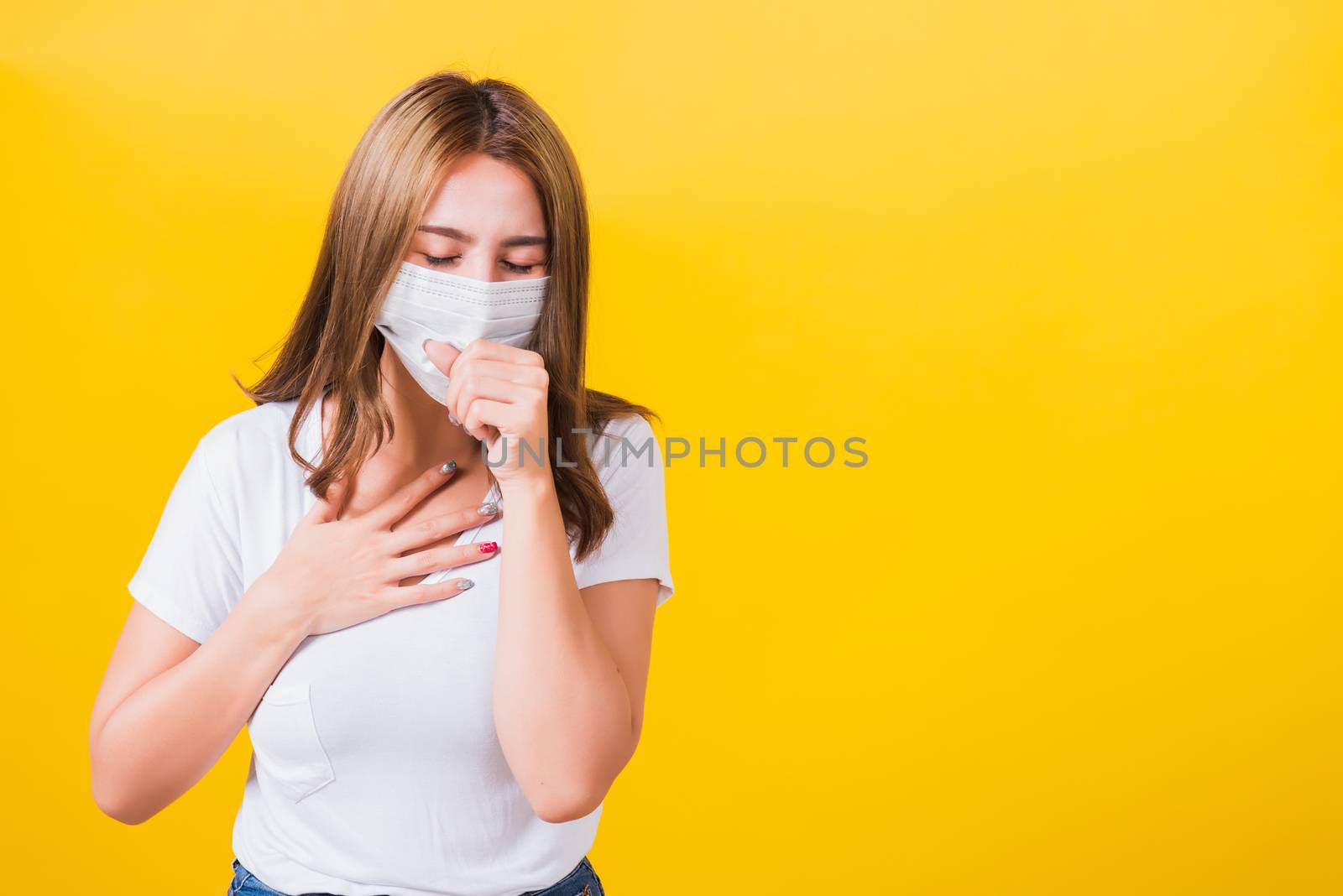 Asian portrait beautiful cute young woman standing wear t-shirt cough in mask protection from COVID virus epidemic or air pollution isolated, studio shot on yellow background with copy space