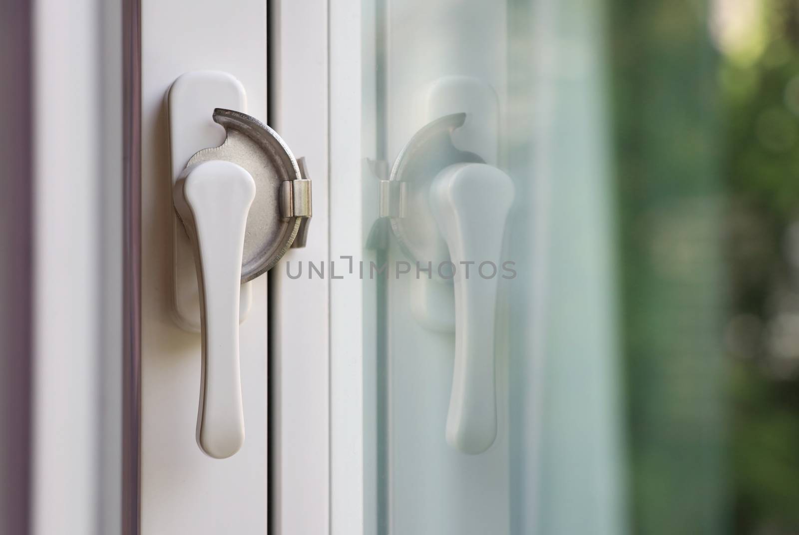 White window lock with mirror reflection. White lever window lock with blurred background.