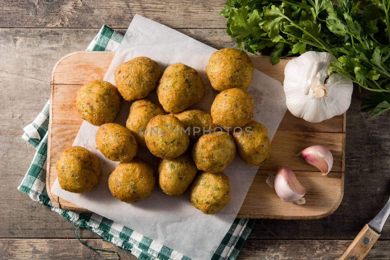 Traditional cod fritters with garlic and parsley on wooden table