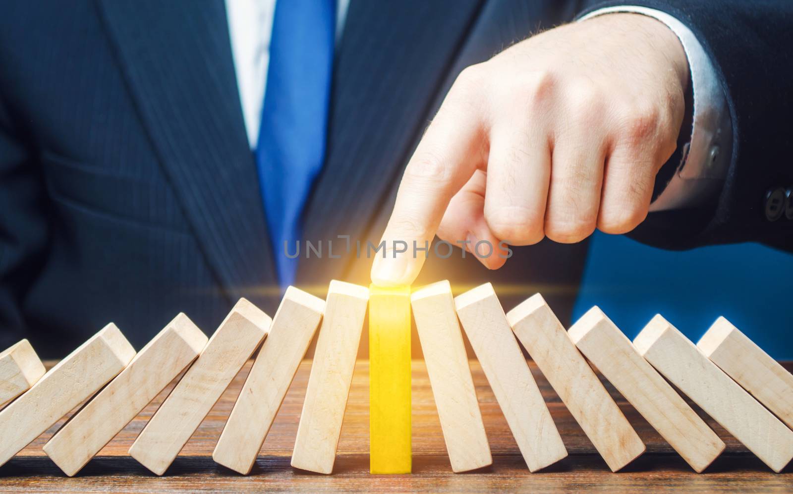 Businessman with a touch stops process of falling dominoes. Successful strong business, solve all accumulated problems. Stop destructive processes. Risk management concept. Debt restructuring