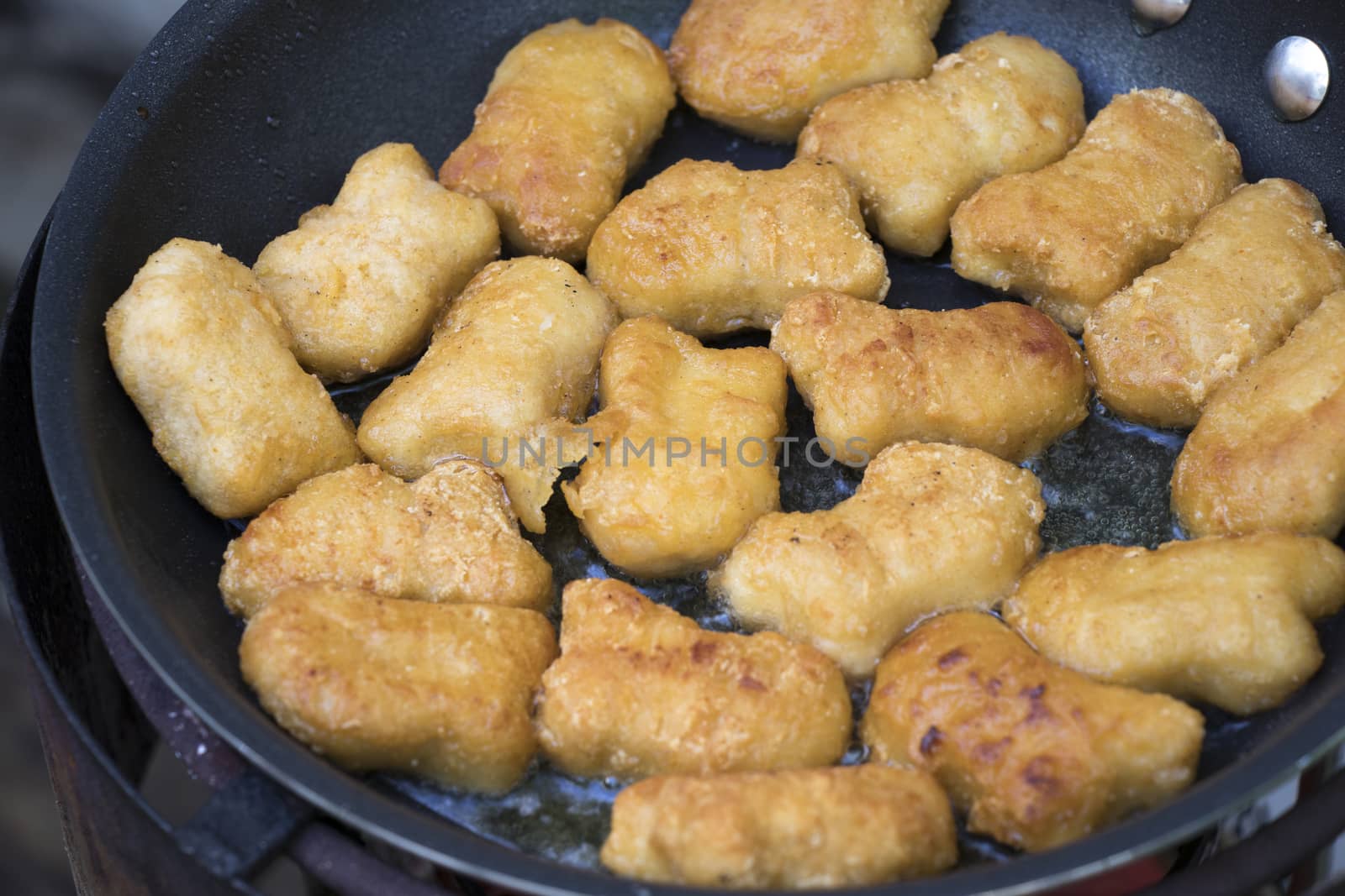 Fried chicken nuggets in the pan with hot oil.