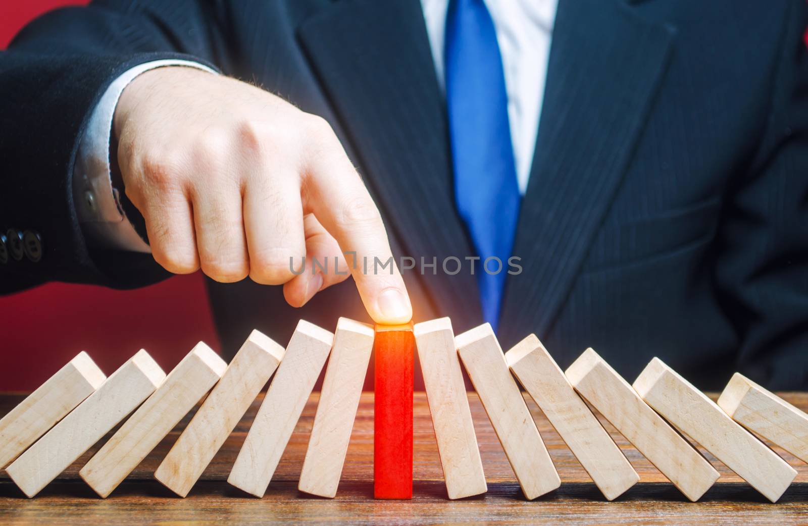 Businessman with a touch stops process of falling dominoes. Risk management concept. Successful strong business, problem solving. Stop destructive processes. Strategy development. Debt restructuring