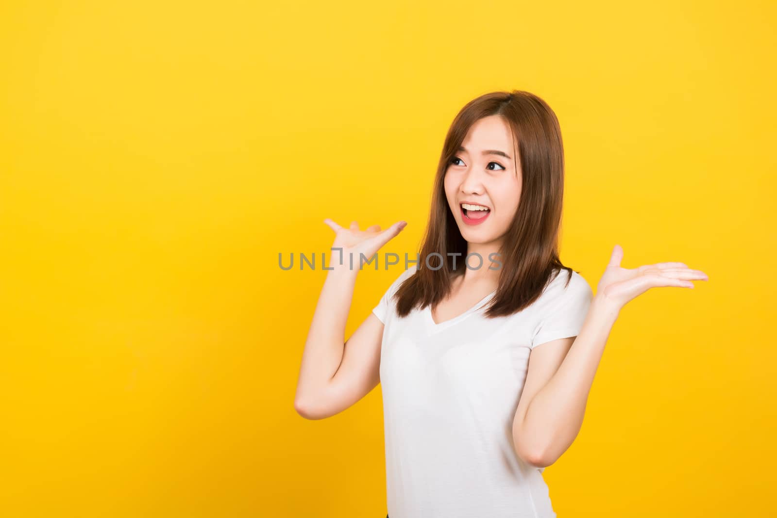 Asian happy portrait beautiful cute young woman teen standing surprised excited screaming open mouth raise hand looking to side away isolated, studio shot on yellow background with copy space