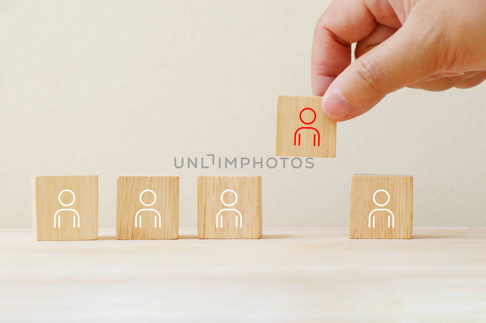 Person icon on wooden cube with hand pick different from them.