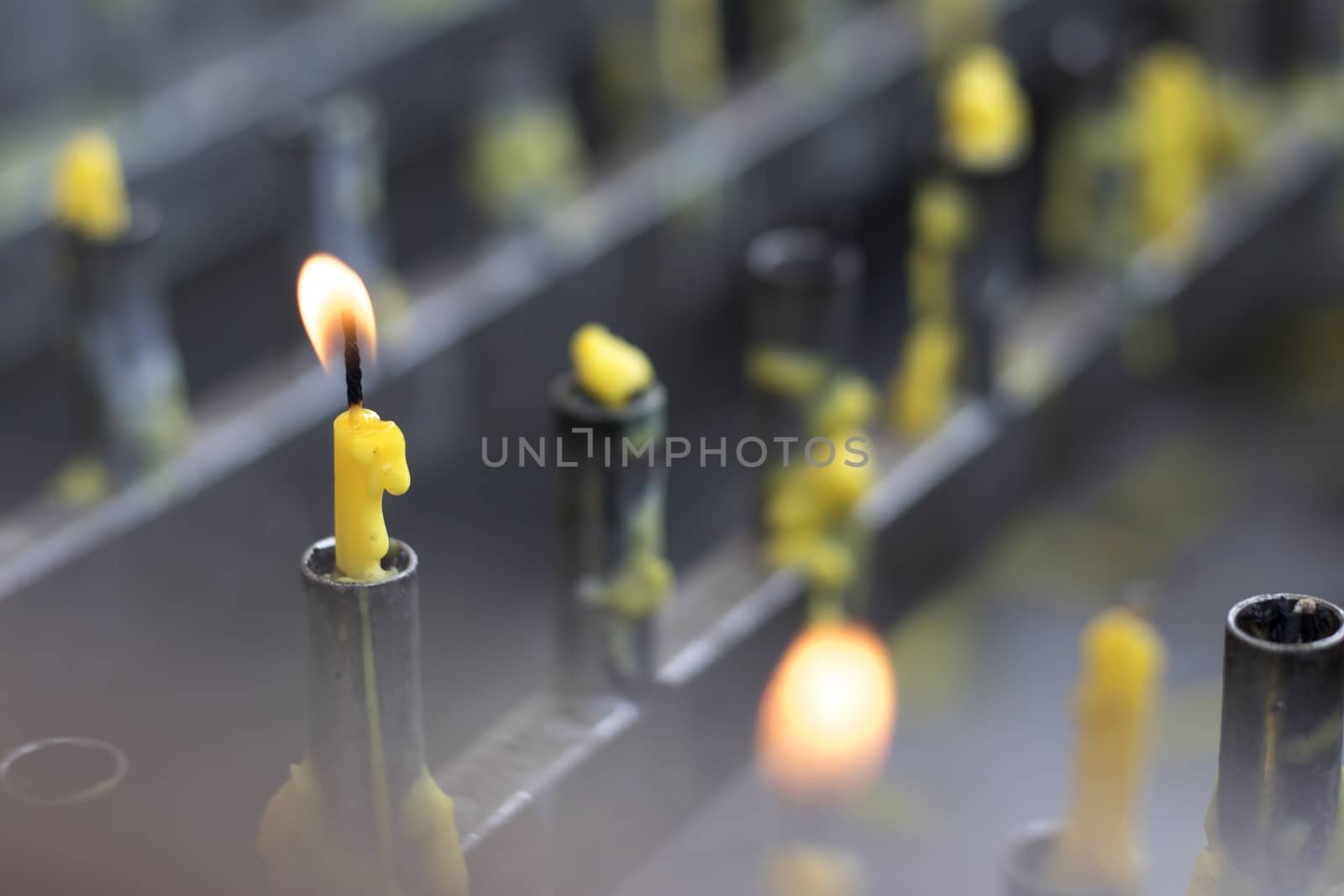 Yellow candles and flames on a candle holder.