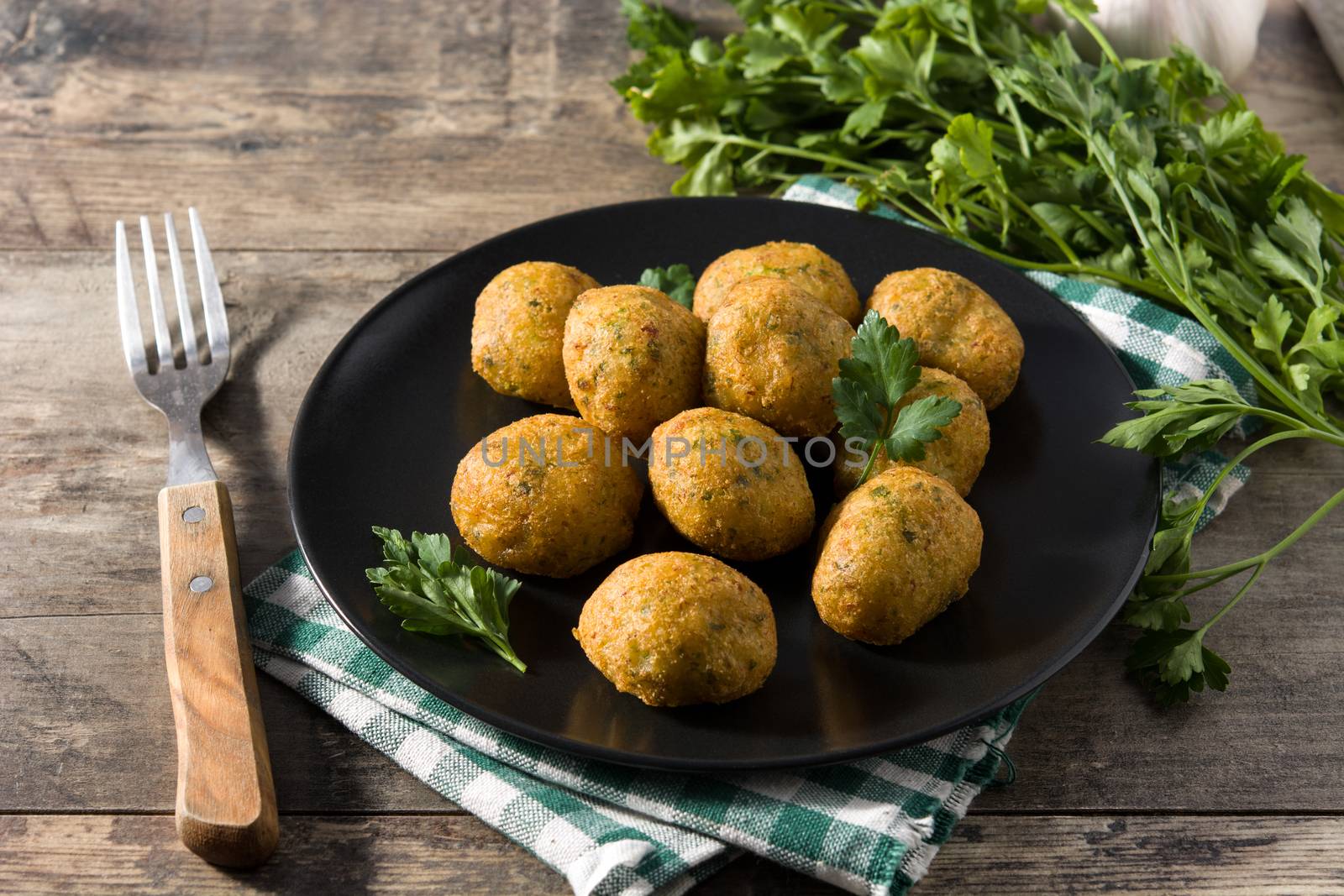 Traditional cod fritters decorated with garlic and parsley on wooden table