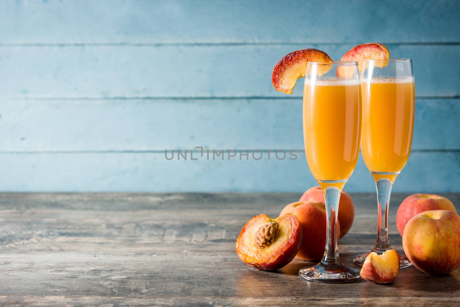 Bellini champagne cocktail in crystal glass on blue wooden table background.Copy space