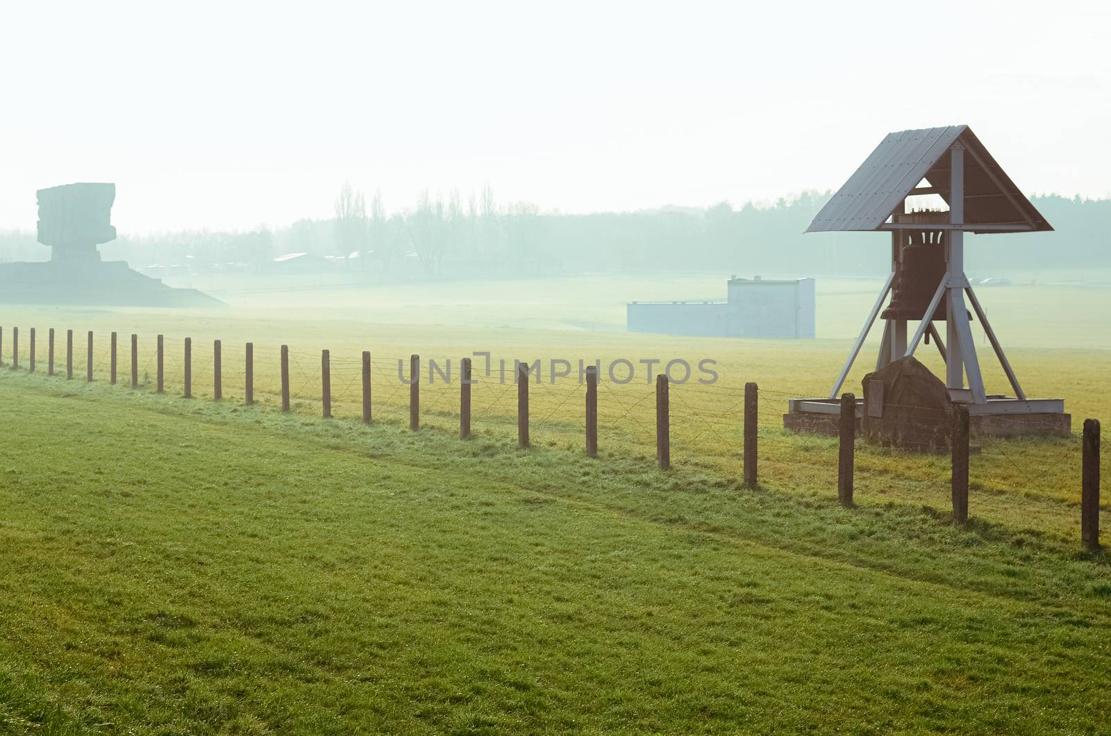 grass field with barbed wire fence and Peace bell in German concentration and extermination camp Majdanek. Lublin, Poland by chernobrovin