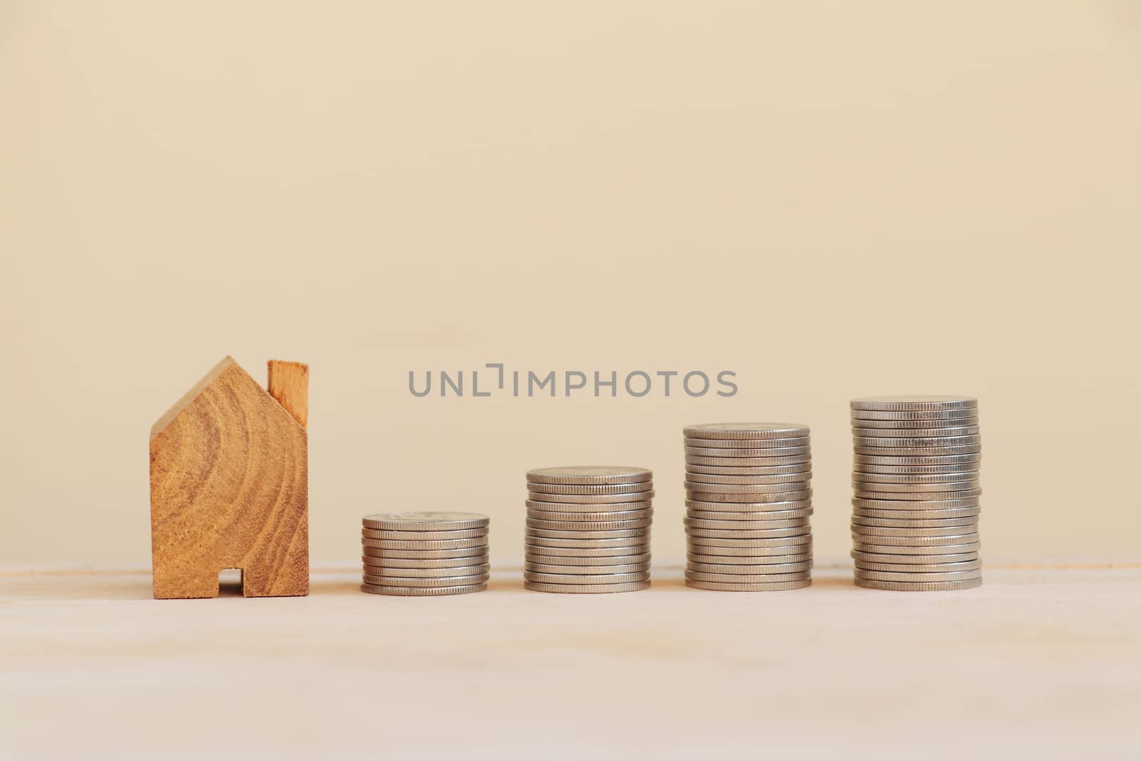 Wooden home with coins arranged in bar graphs. Savings for buying a house concept.