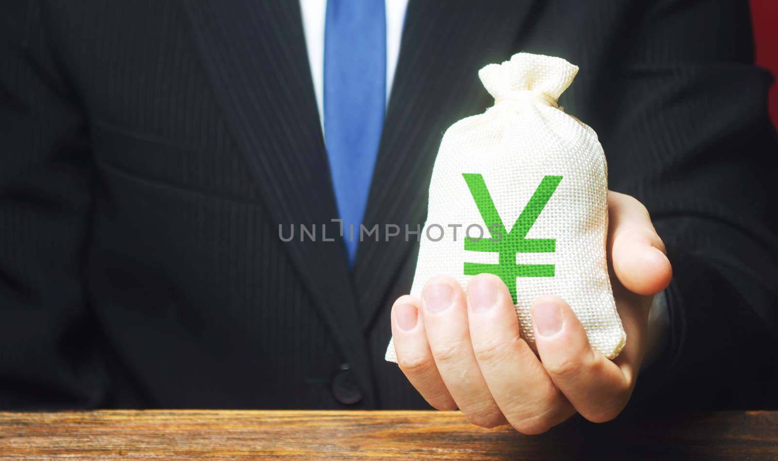Man holds out a Yen yuan money bag. Provision of money on credit, grant. Project financing. Donations. Financial social assistance. Payment purchases, profits dividends. Business investment by iLixe48