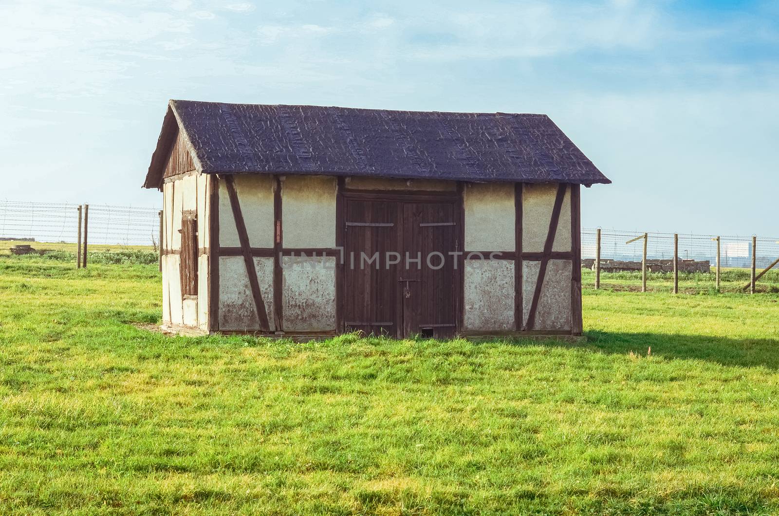 old barn on grassy green field in German concentration and extermination camp Majdanek. Lublin, Poland by chernobrovin