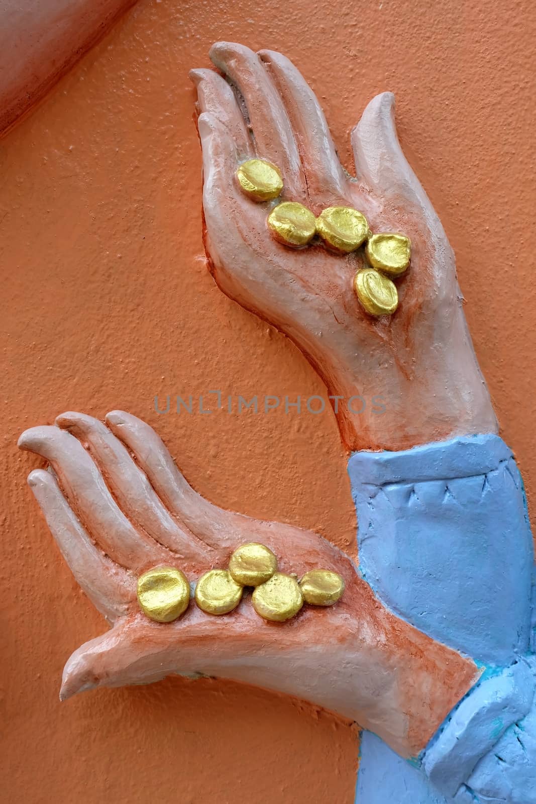 Close up Golden Coins in Sculpture Hand on Concrete Wall. by mesamong