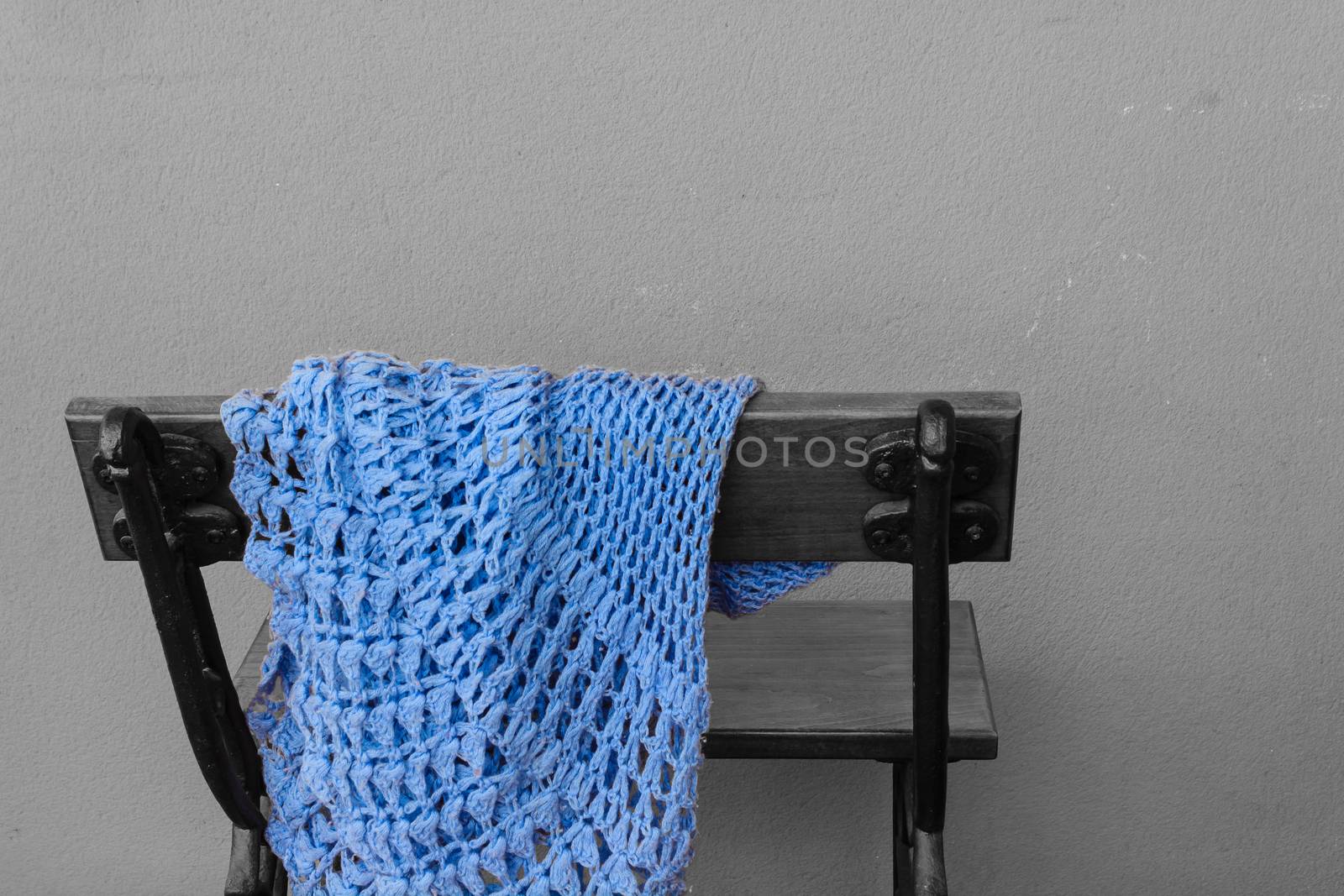 a wooden bench with with a woolen shawl blue  abandoned on the back