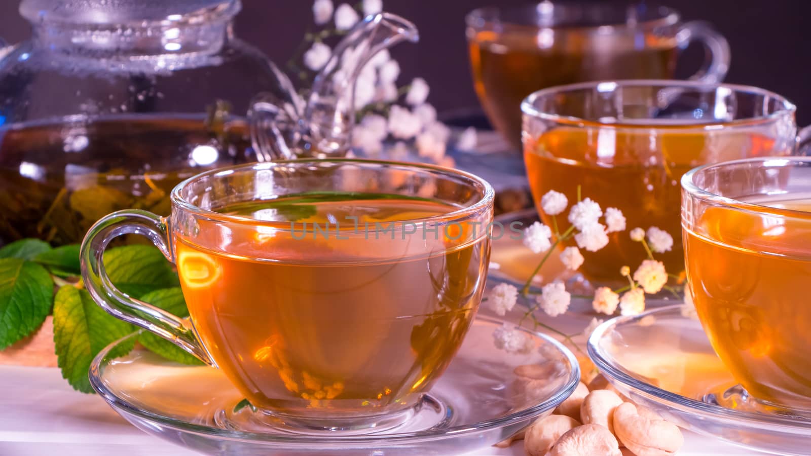 Teapot and mugs with green tea, cashew nuts, green leaves and white gypsophila flowers.Tea ceremony, traditional drink. Afternoon tea, homelike. Oriental, cozy, preparation, japanese, leafy, herbal