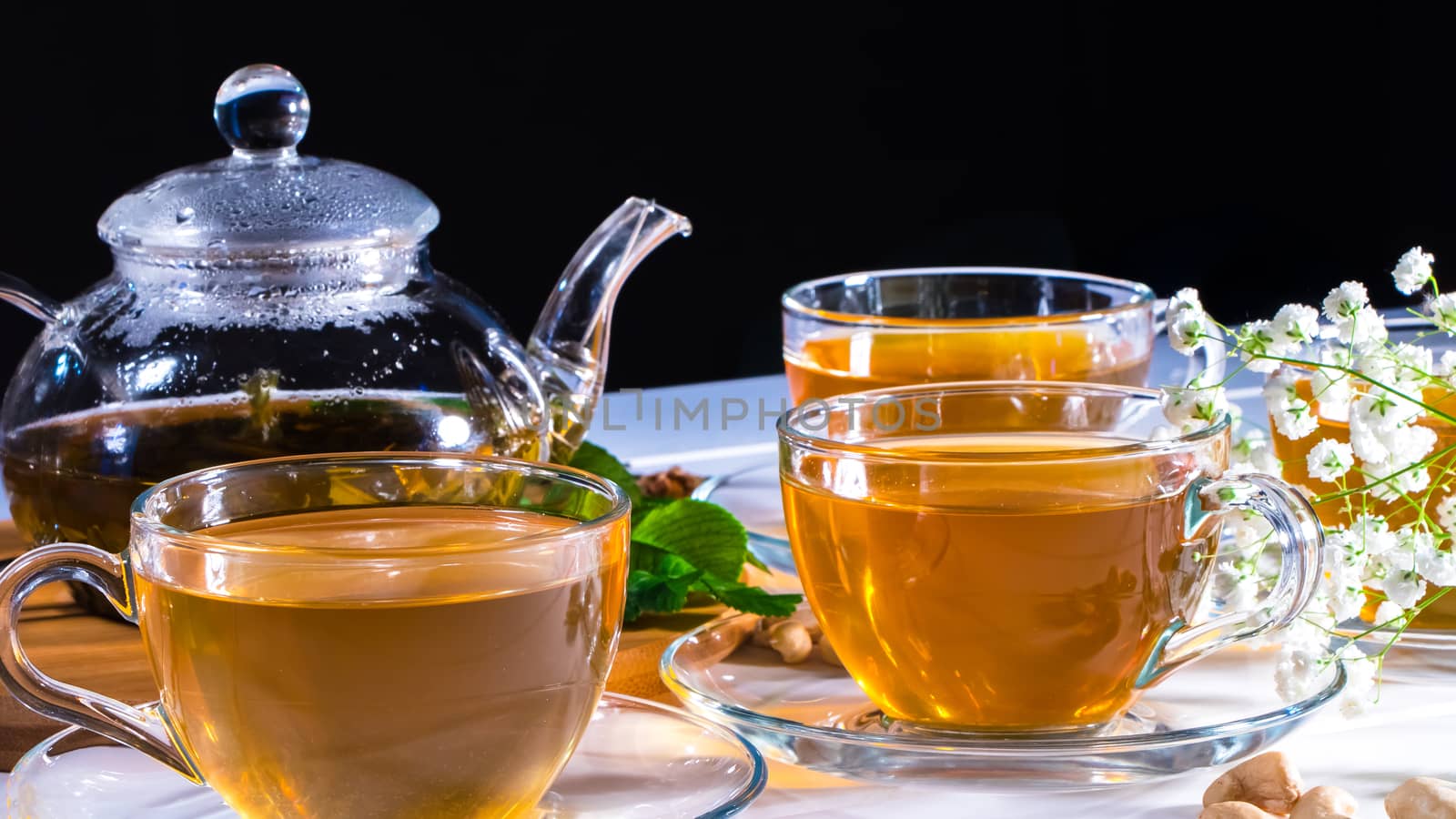 Teapot and mugs with green tea, cashew nuts, green leaves and white gypsophila flowers.Tea ceremony, traditional drink. Afternoon tea, homelike. Oriental, cozy, preparation, japanese, leafy, herbal