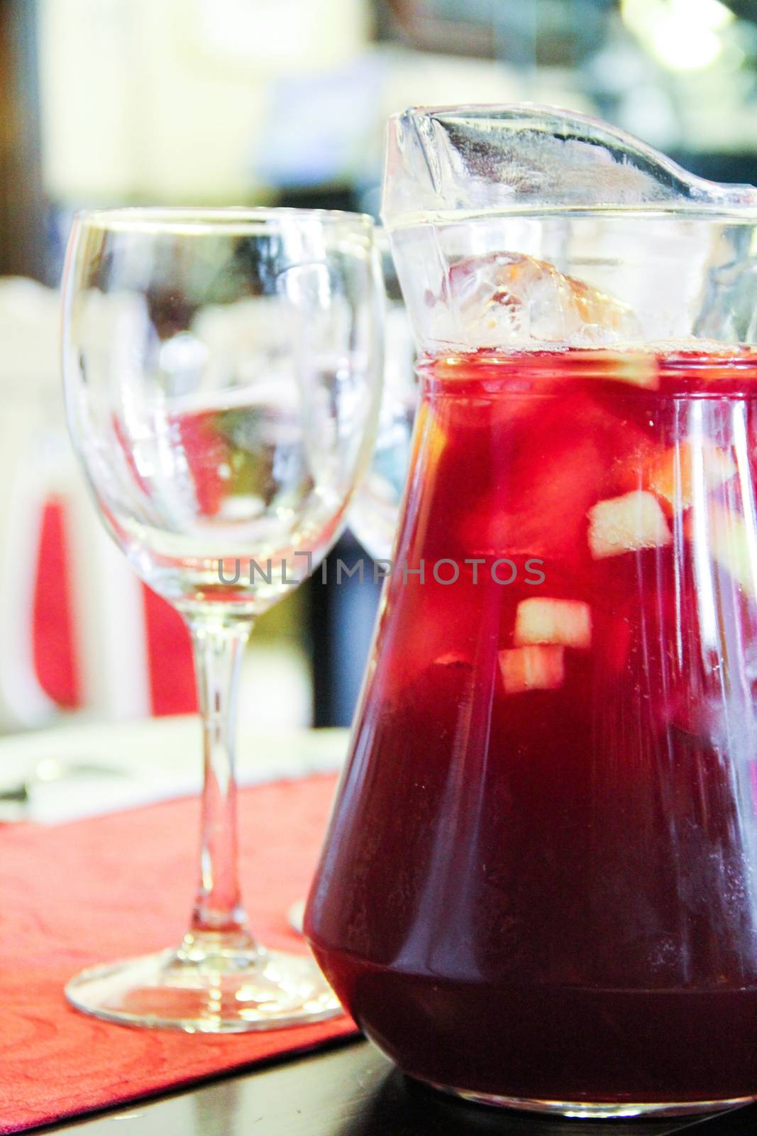 Glass and jar filled with sangria in the background in restaurant