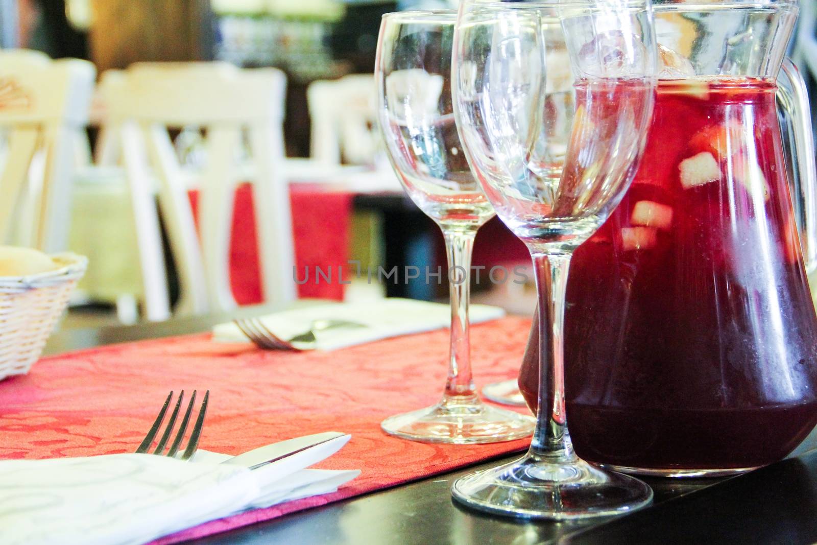 Glass and jar filled with sangria in the background in restaurant