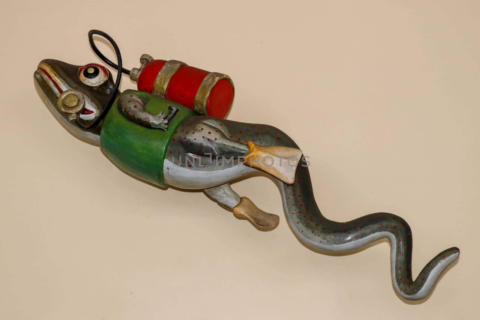 Statue of gecko with diving equipment on the wall of diving center. 3D gecko as a diver. Lizard figurine with green jacket, red diving tank and yellow fins. A funny accessory in the diving base area.