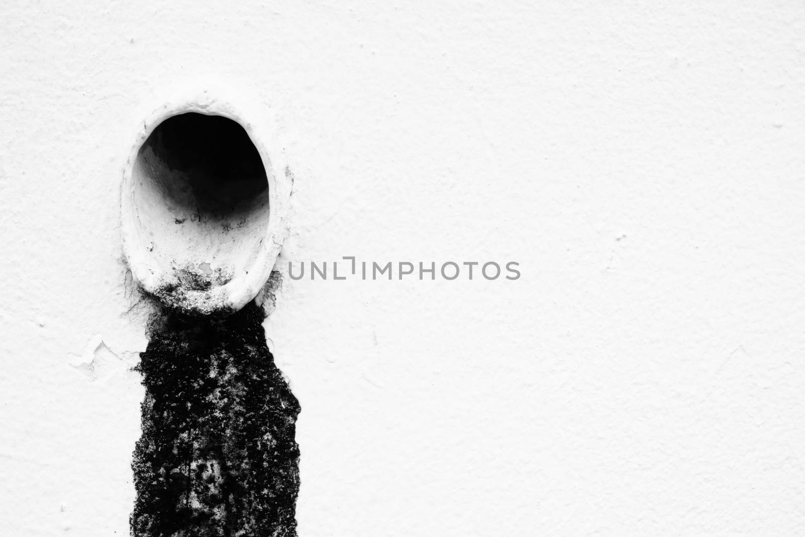 Black Sludge from Drain with White Paint Concrete Background.