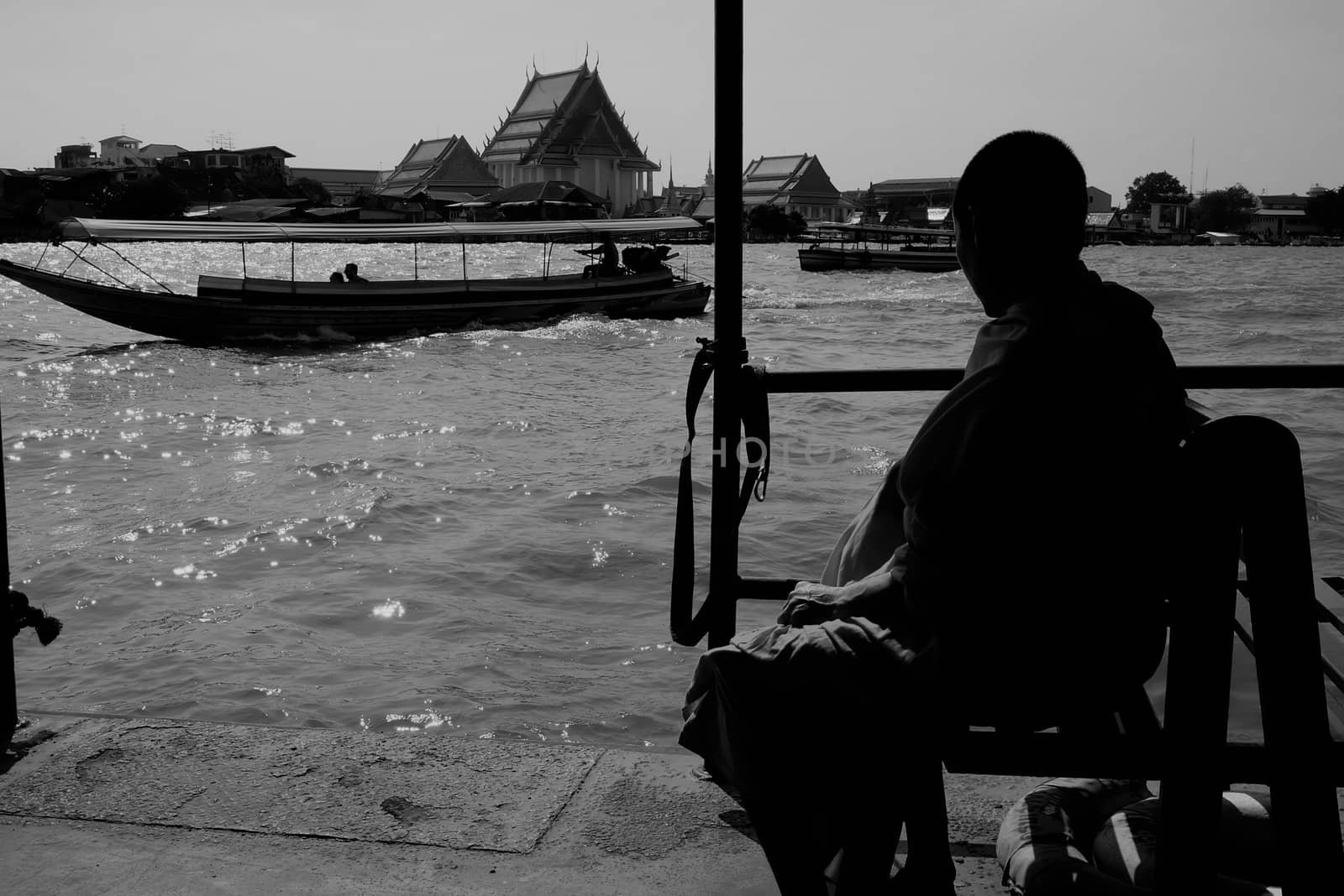 Silhouette of Buddhist Monk Sitting in Ferry Boat at Chao Phya River Bangkok, Thailnad in Black and White. Translation Texts in Image is "Marine Department or Lifeguard". by mesamong