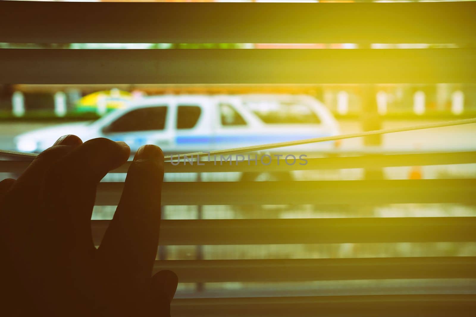 Hand Opening Window Blind with Sunlight Beam to See Car outside House. by mesamong