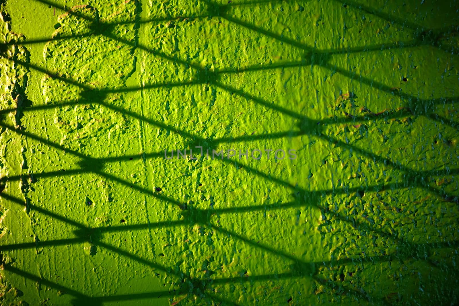 Metal Wire Fence Shadow on Green Concrete Wall Background.