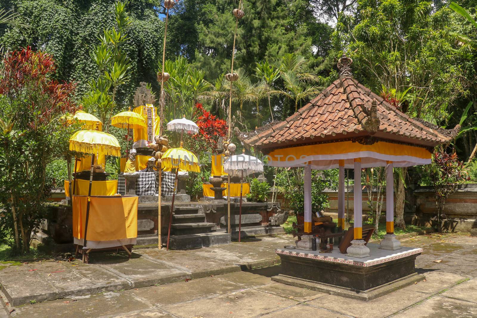 Hindu temple near to Batukaru temple on Bali island in Indonesia. Tabernacle of the Believing Balinese. Balinese culture, closeup of yellow and white decorative umbrelas among tropical plants.