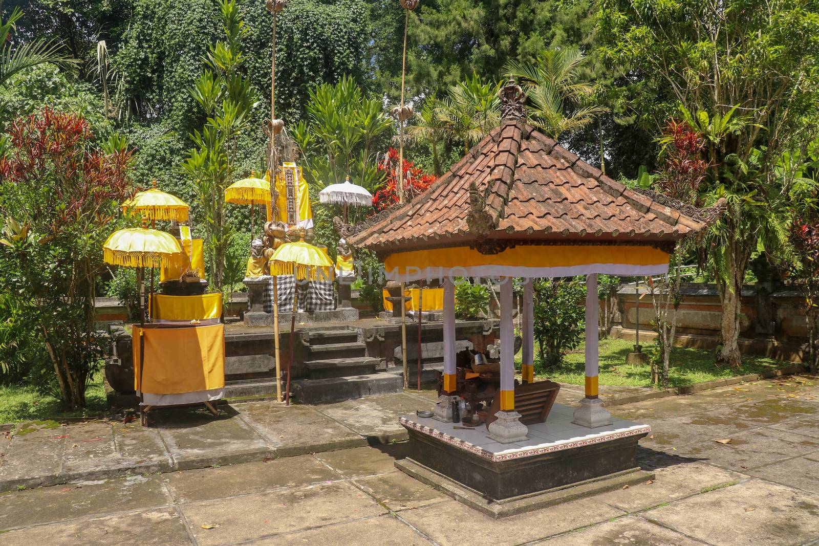 Hindu temple near to Batukaru temple on Bali island in Indonesia. Tabernacle of the Believing Balinese. Balinese culture, closeup of yellow and white decorative umbrelas among tropical plants.