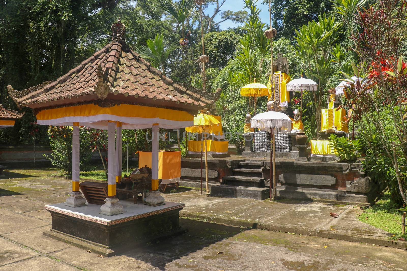 Hindu temple near to Batukaru temple on Bali island in Indonesia. Tabernacle of the Believing Balinese. Balinese culture, closeup of yellow and white decorative umbrelas among tropical plants.