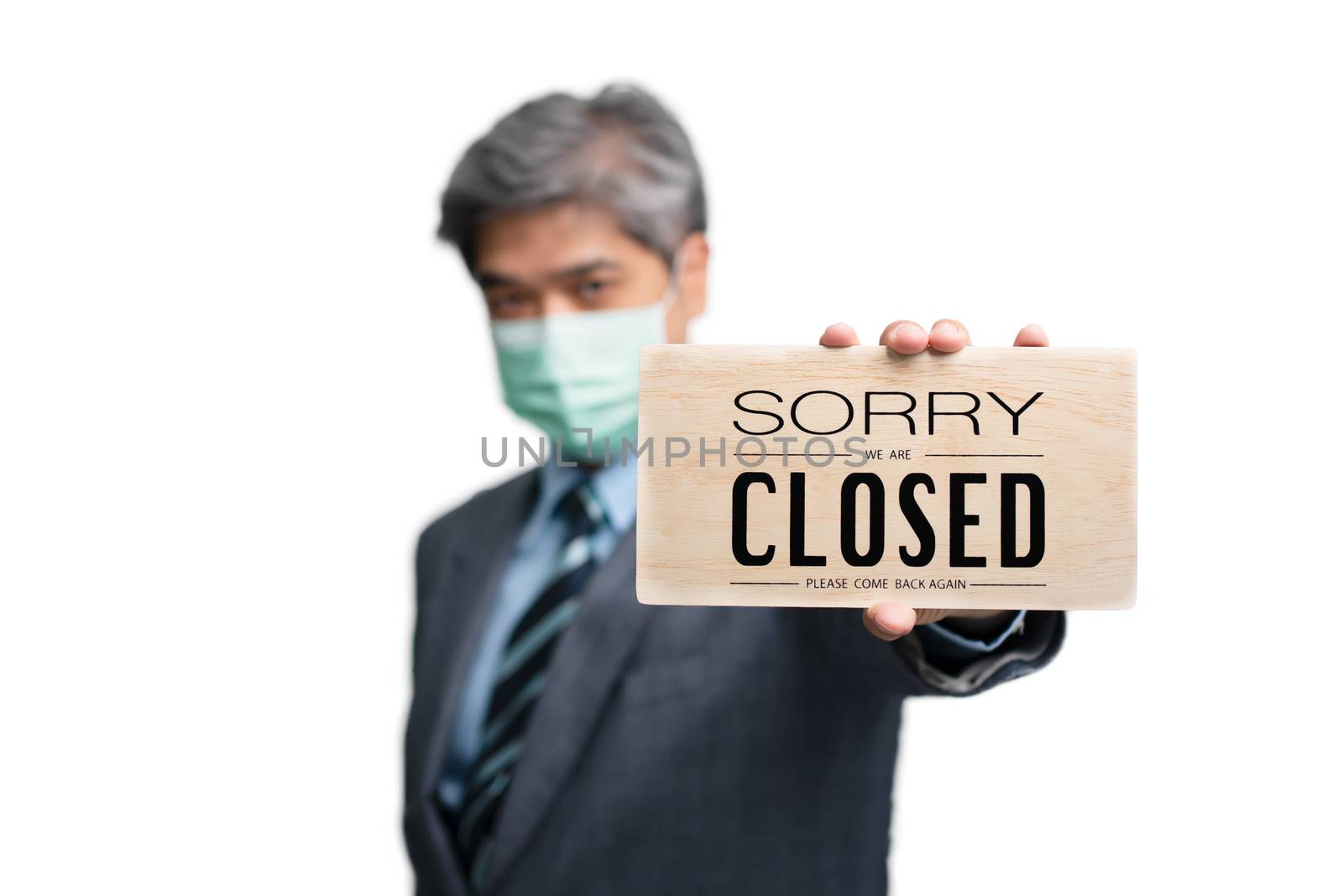 Businessmen wear medical masks on the isolated background and holding sorry we are closed sign. Concept of businesses and shops have to close because of a virus epidemic and quarantine