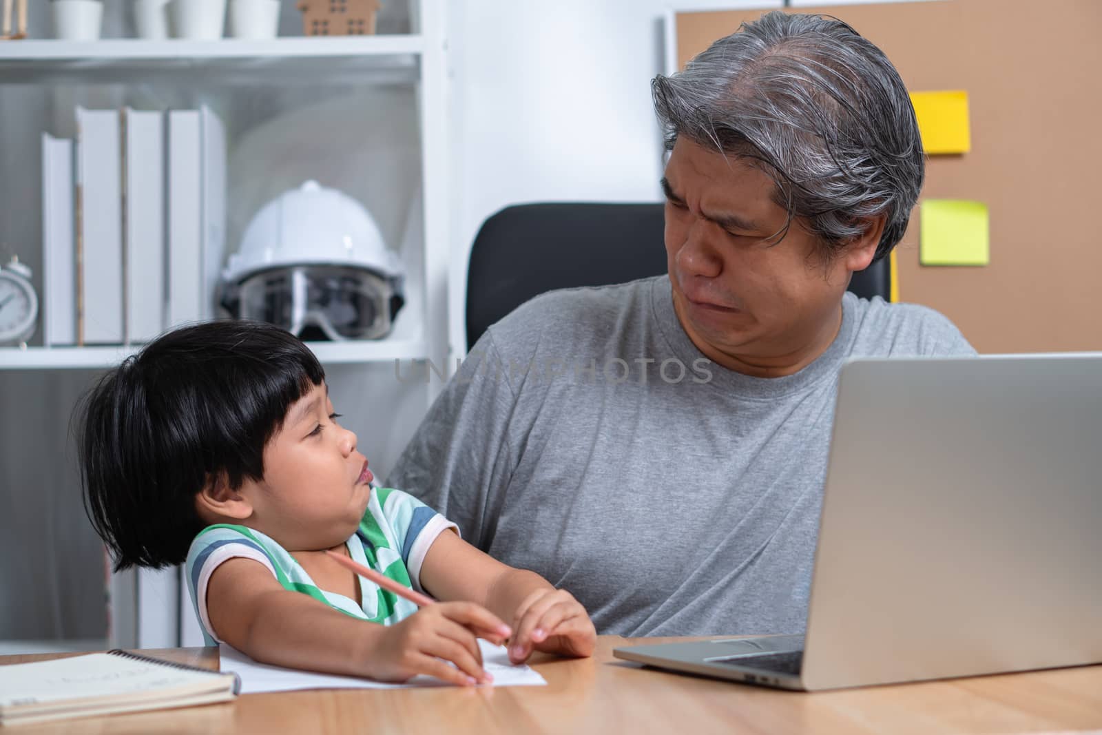Asian father attempt to work at the home office with a laptop with a daughter who came into chaos. New lifestyle normal during a quarantine. Concept of stay home, freelance and fatherhood concept
