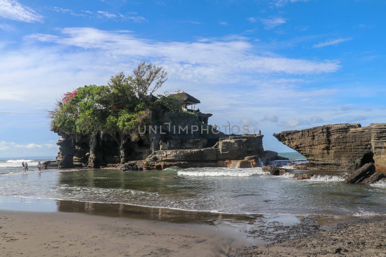 Sacred Balinese temple in Tanah Lot. Pura Batu Bolong on coastline with hole in rock. Traditional style and architecture of Bali. Holy place for local indonesian people