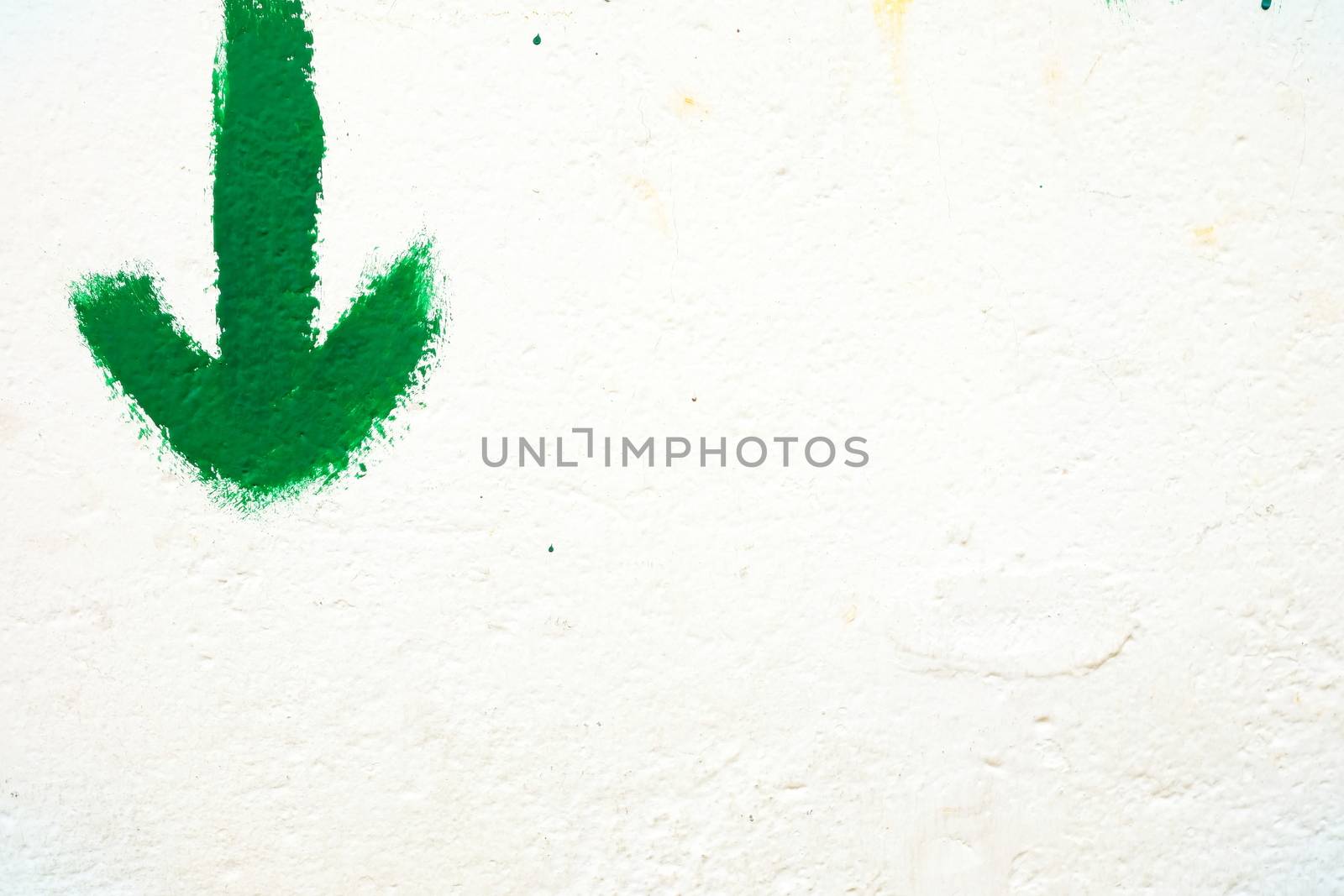 Green Arrow on White Concrete Wall Background. by mesamong
