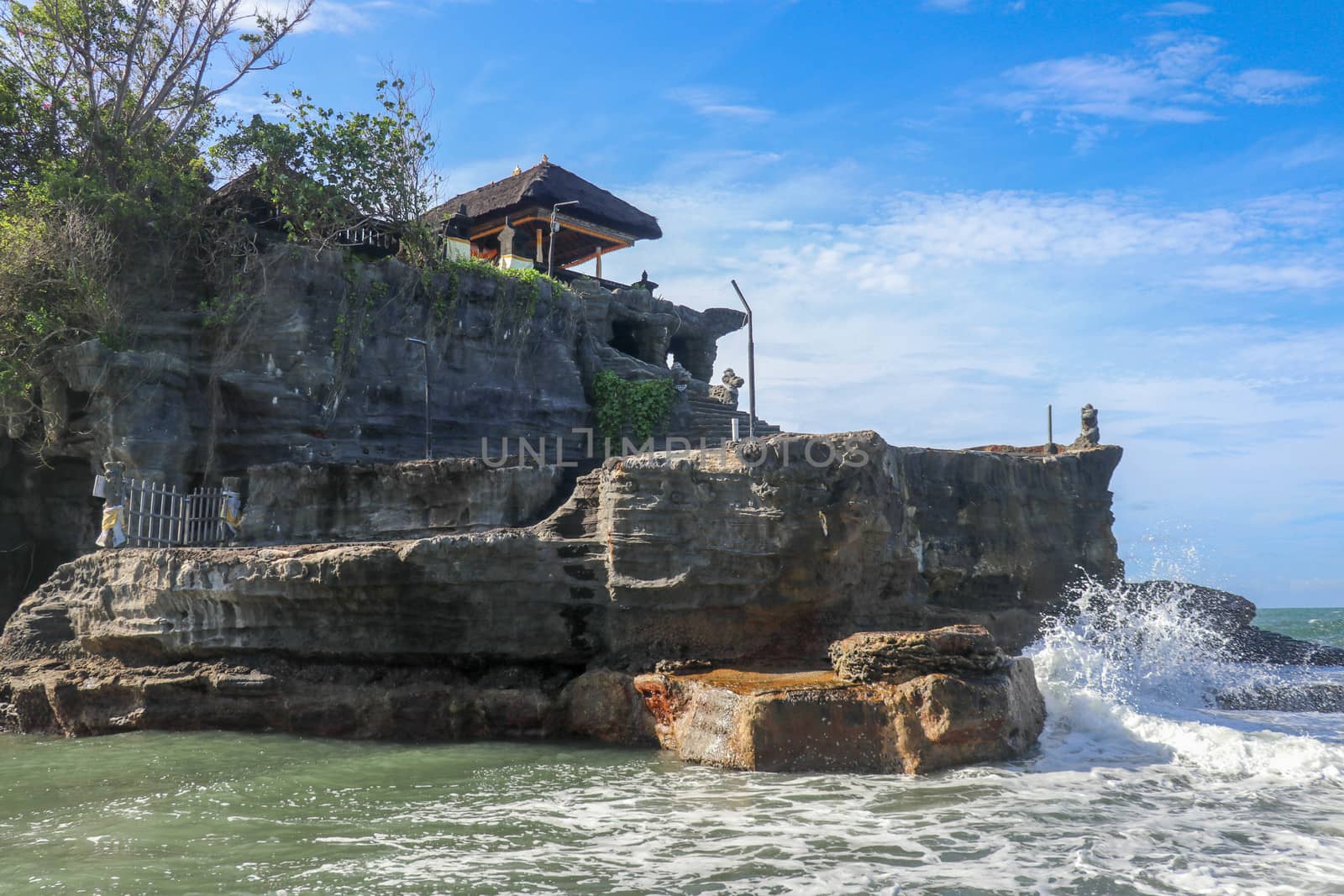 Beautiful balinese landscape. Ancient hinduism temple Tanah lot on the rock against sunset sky. Bali Island, Indonesia. famous Tanah Lot Temple on Sea in Bali Island Indonesia with blue sky and waves.