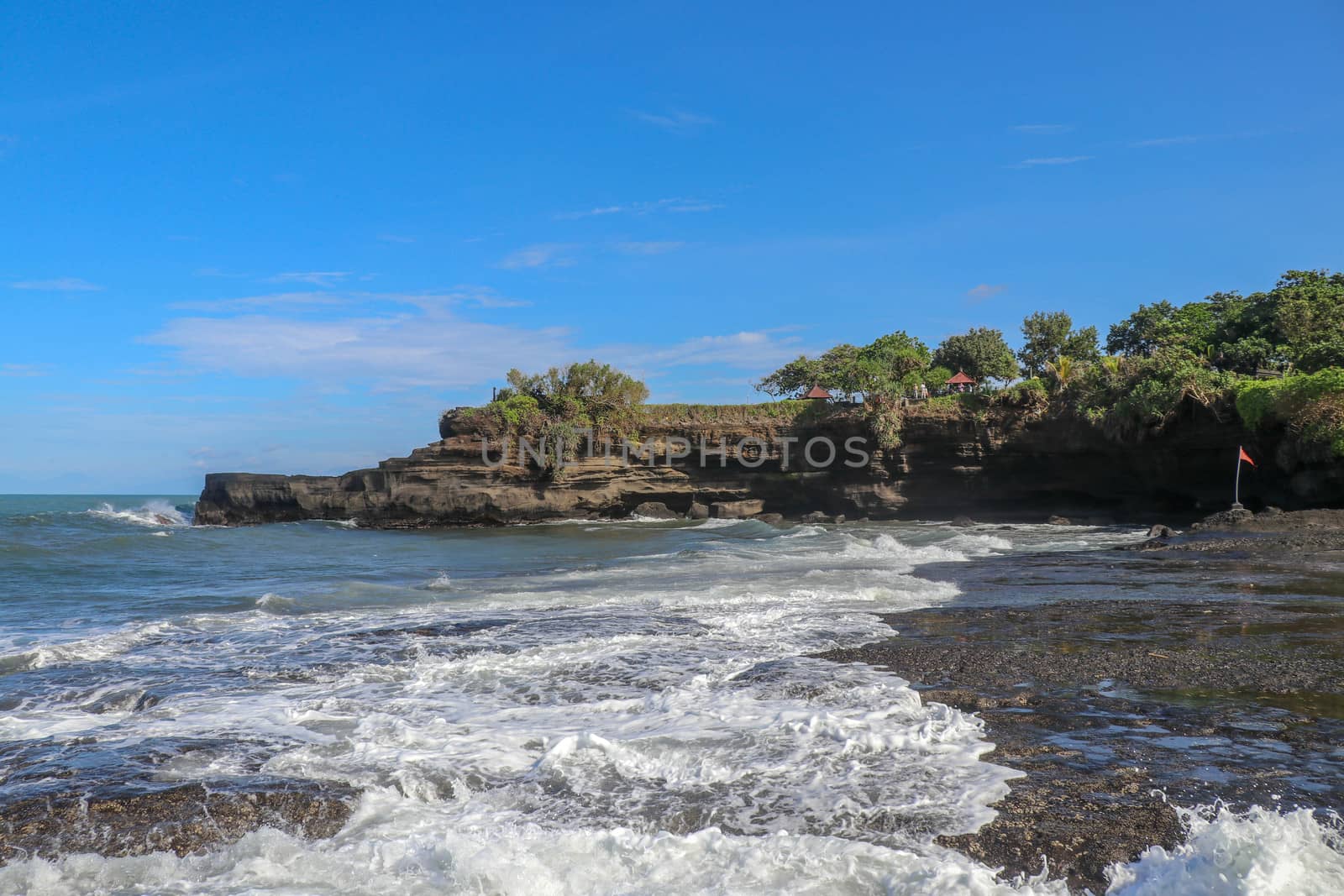 Indian Ocean coast near the Sacred Balinese temple Tanah Lot. Pura Batu Bolong on the edge of a cliff at coastline with hole in the rock. Holy place for local indonesian people