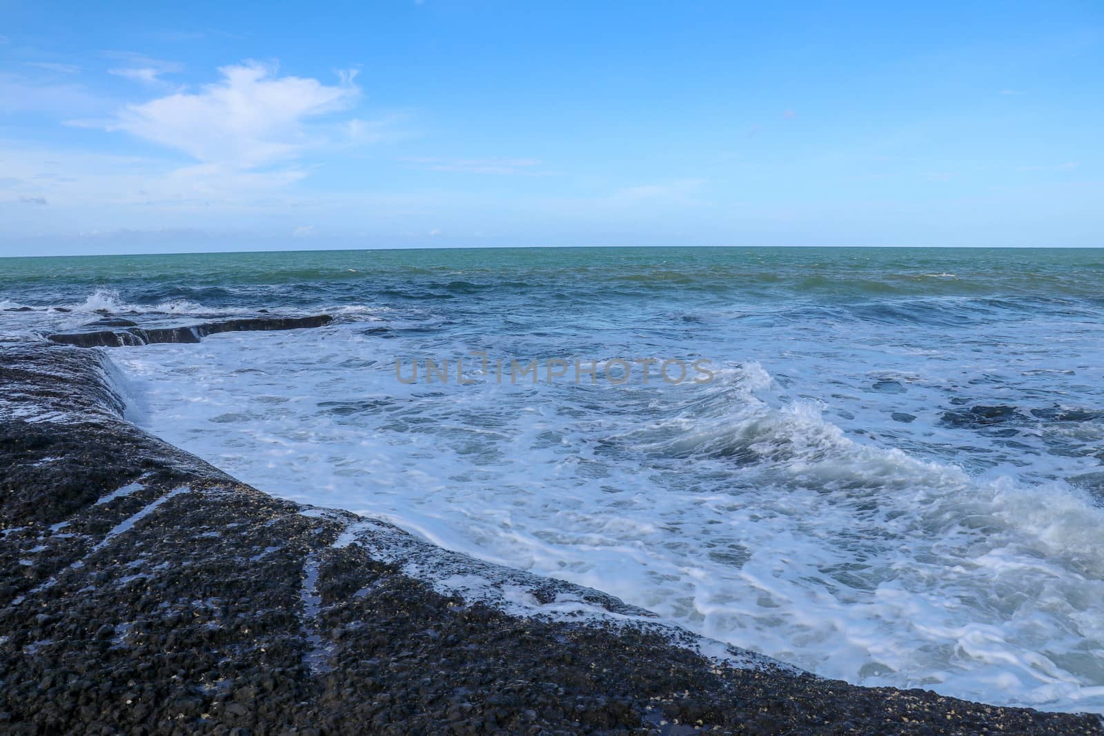 Indian Ocean coast near the Sacred Balinese temple Tanah Lot. Pura Batu Bolong on the edge of a cliff at coastline with hole in the rock. Holy place for local indonesian people