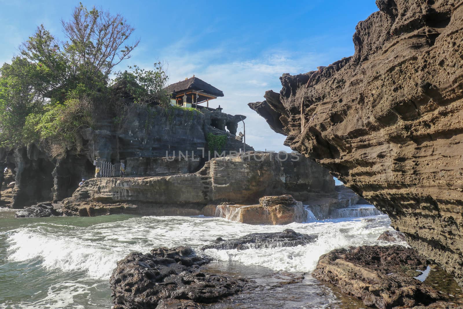 Beautiful balinese landscape. Ancient hinduism temple Tanah lot on the rock against sunset sky. Bali Island, Indonesia. famous Tanah Lot Temple on Sea in Bali Island Indonesia with blue sky and waves.