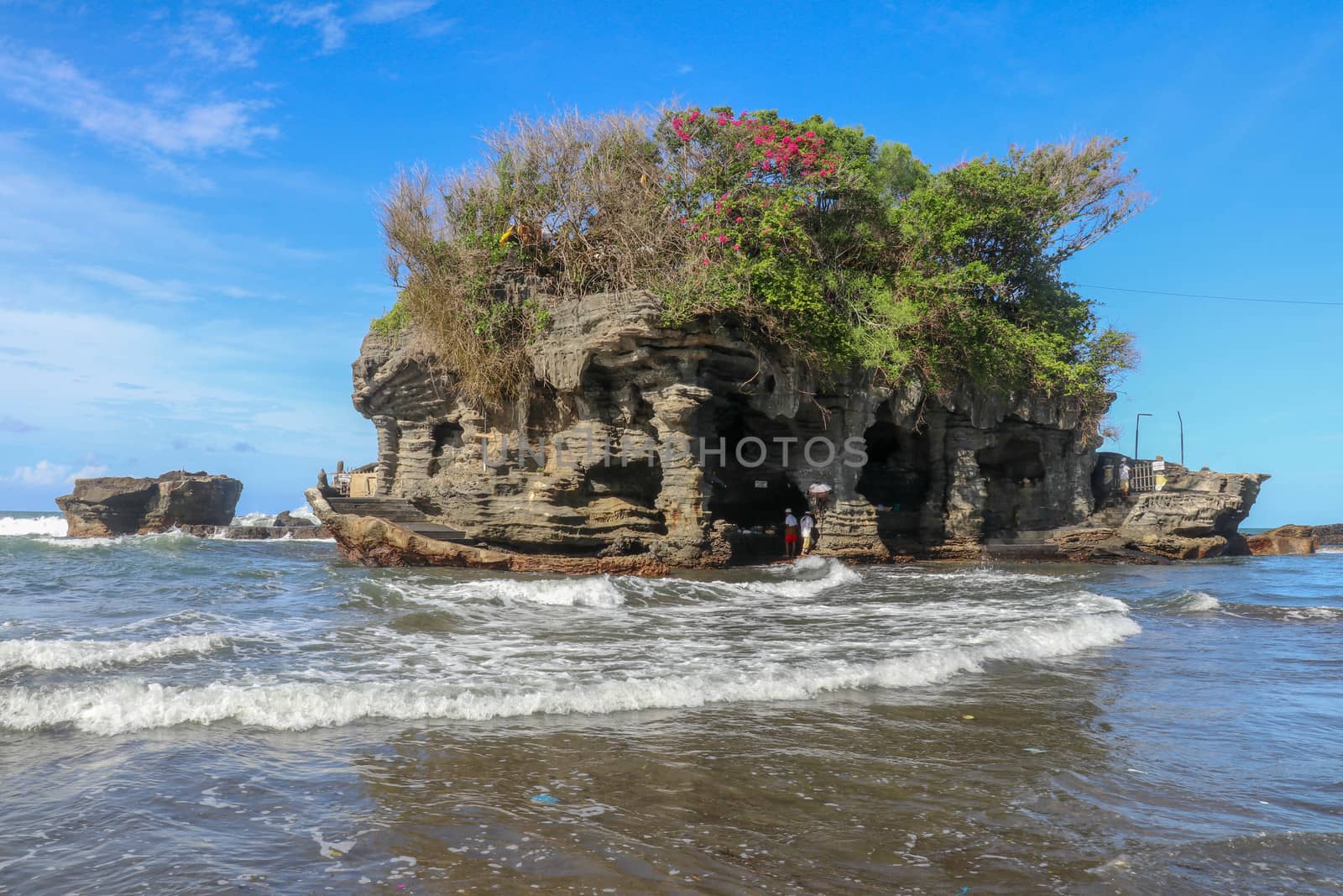 Sacred Balinese temple in Tanah Lot. Pura Batu Bolong on coastline with hole in rock. Traditional style and architecture of Bali. Holy place for local indonesian people