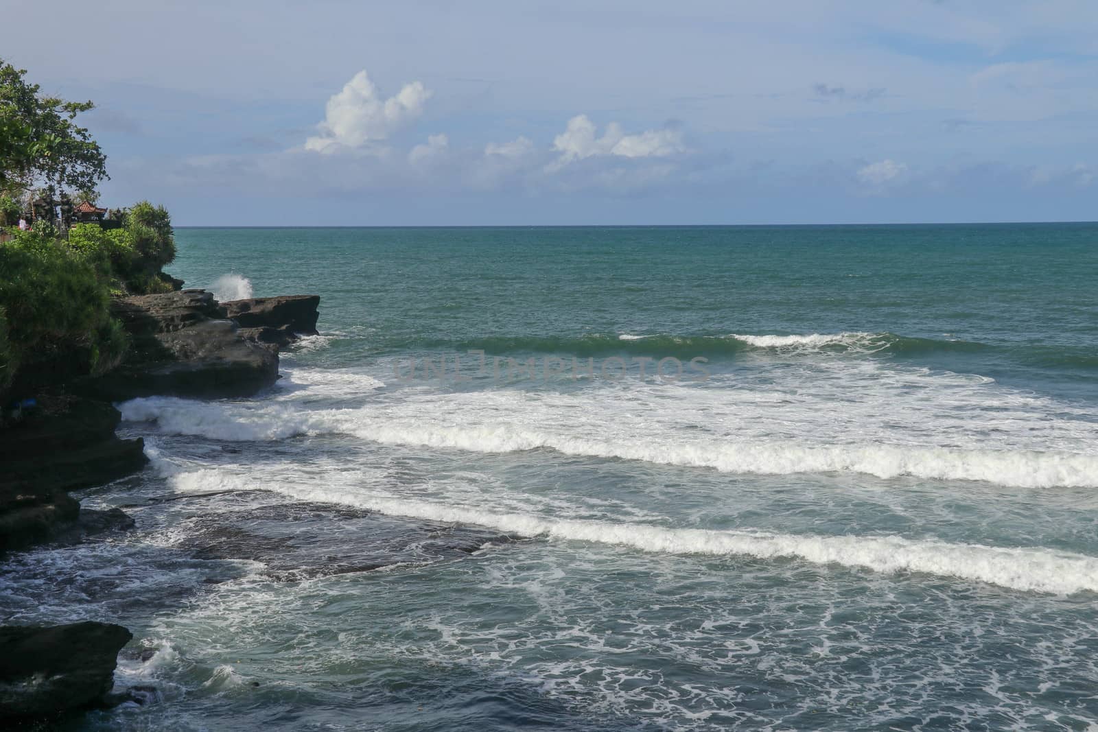 Indian Ocean coast near the Sacred Balinese temple Tanah Lot. Pura Batu Bolong on the edge of a cliff at coastline with hole in the rock. Holy place for local indonesian people