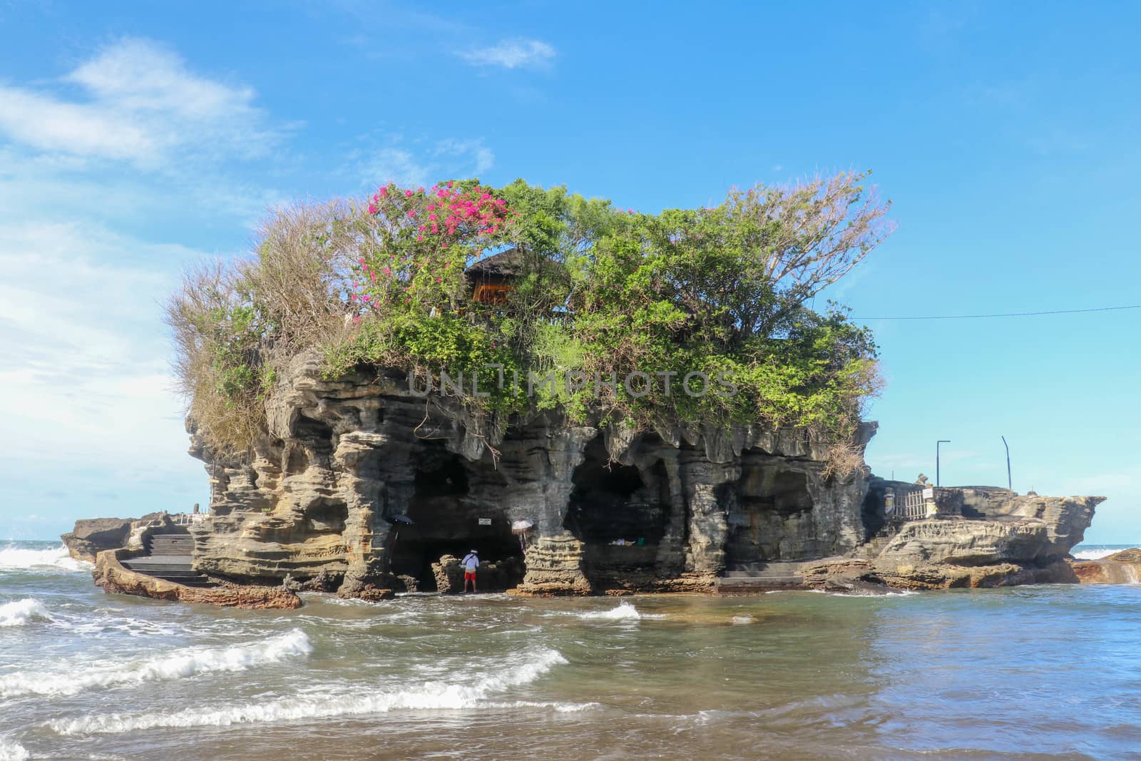 Sacred Balinese temple in Tanah Lot. Pura Batu Bolong on coastline with hole in rock. Traditional style and architecture of Bali. Holy place for local indonesian people