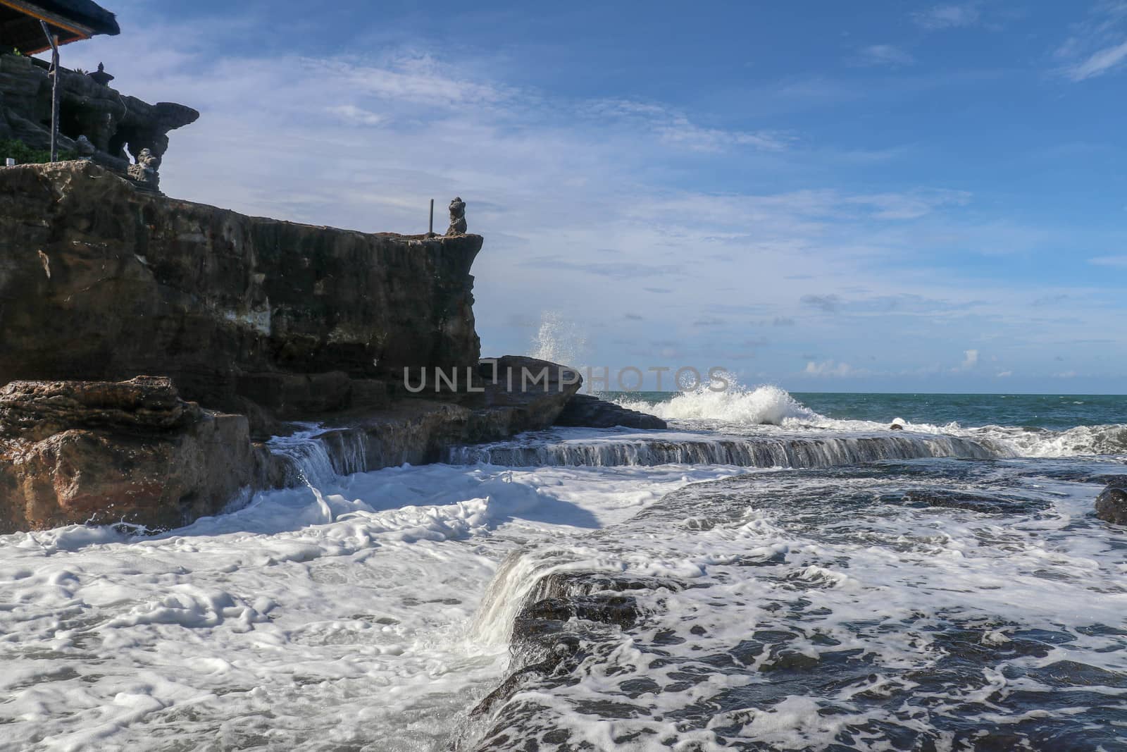 Beautiful balinese landscape. Ancient hinduism temple Tanah lot on the rock against sunset sky. Bali Island, Indonesia. famous Tanah Lot Temple on Sea in Bali Island Indonesia with blue sky and waves.