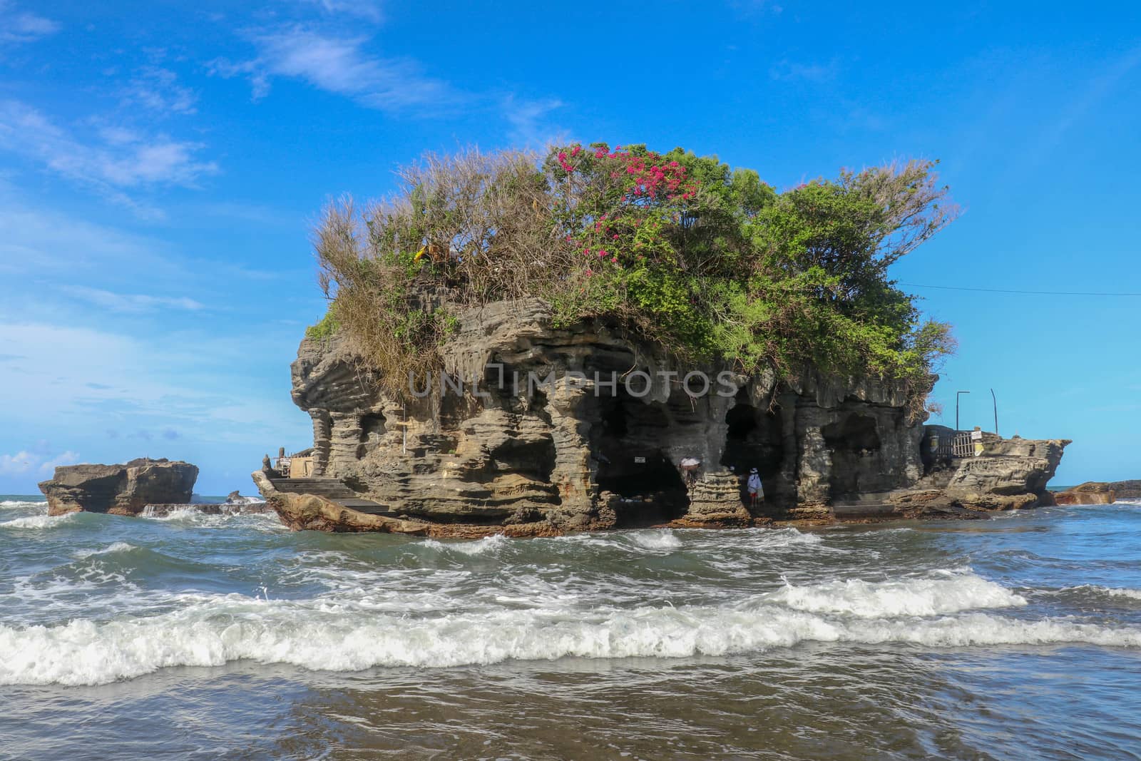 Sacred Balinese temple in Tanah Lot. Pura Batu Bolong on coastline with hole in rock. Traditional style and architecture of Bali. Holy place for local indonesian people
